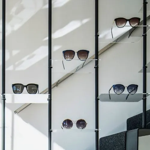 Muestra de gafas de sol expuestas en estantería de cristal en Sensia Óptica, Vera