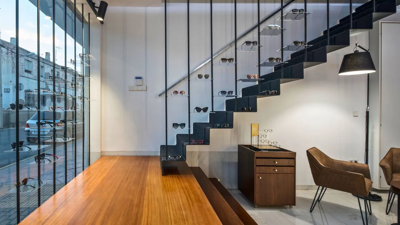 Interior de Sensia Óptica con gafas de diseño expuestas en la escalera, Vera