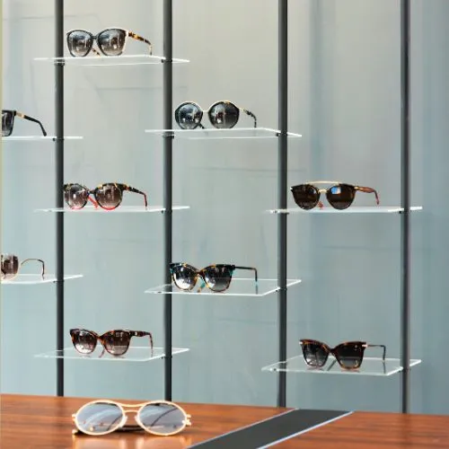 Gafas de diseño expuestas en estantes de cristal en Sensia Optics en Vera